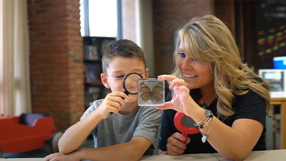 Woman looking at butterfly with young boy in library