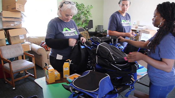 Bankers stuffing backpacks with supplies